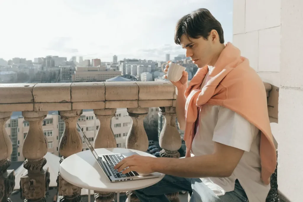 Muž s notebookem na balkoně