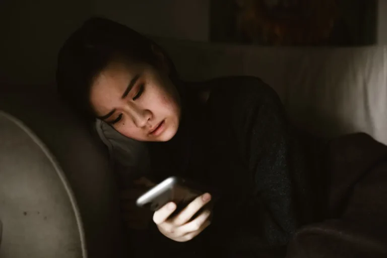 Člověk drží telefon doma na gauči